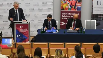 3 people talking in front of an audience in a conference hall.