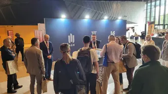 Grupa ludzi stoi przy stanowisku promocyjnym
